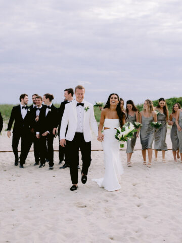 A newly wed couple surrounded by friends at a beach.