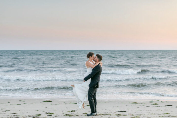 A bride and groom sharing a kiss by the beach.