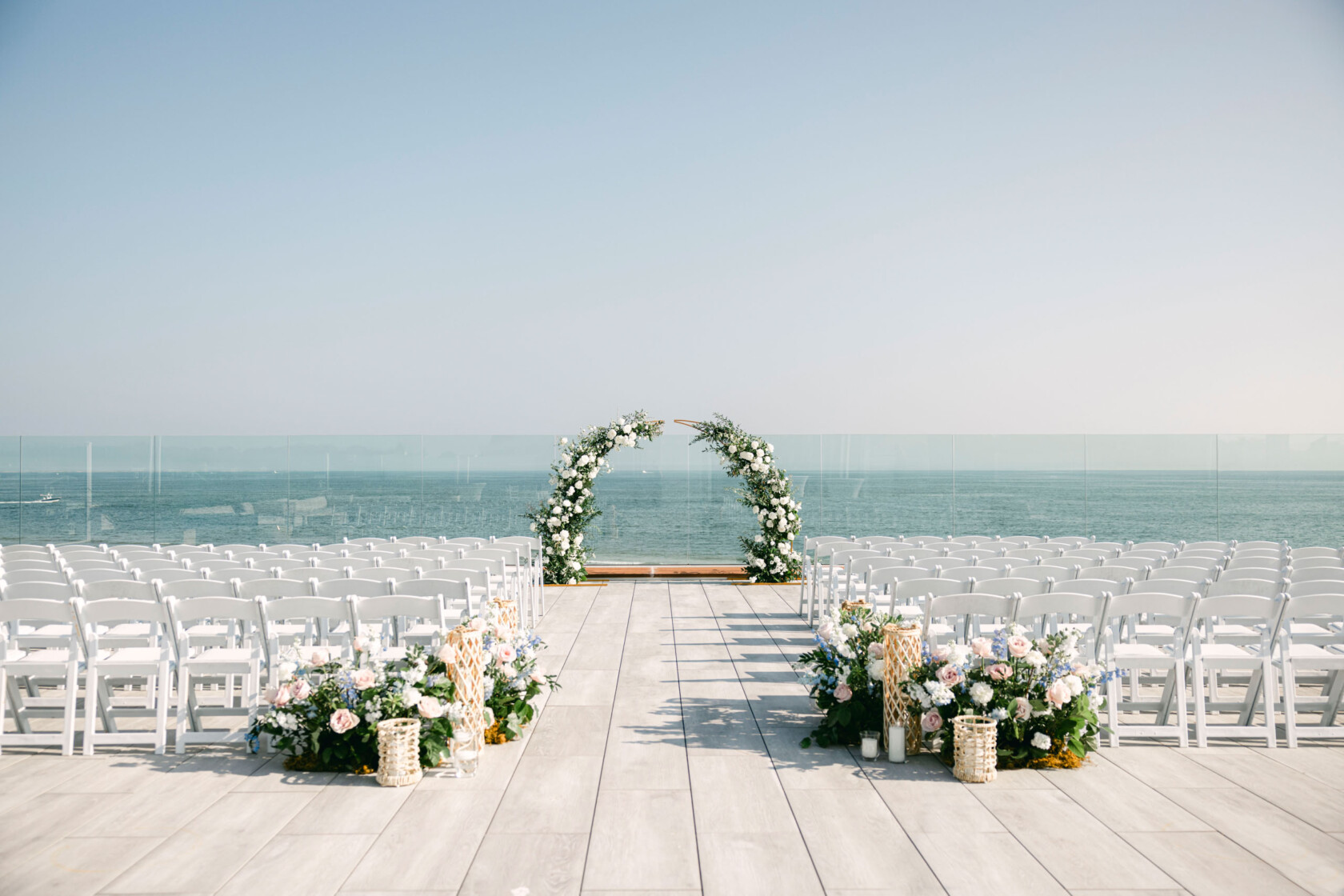wedding ceremony setup with a flower arch on a beach.